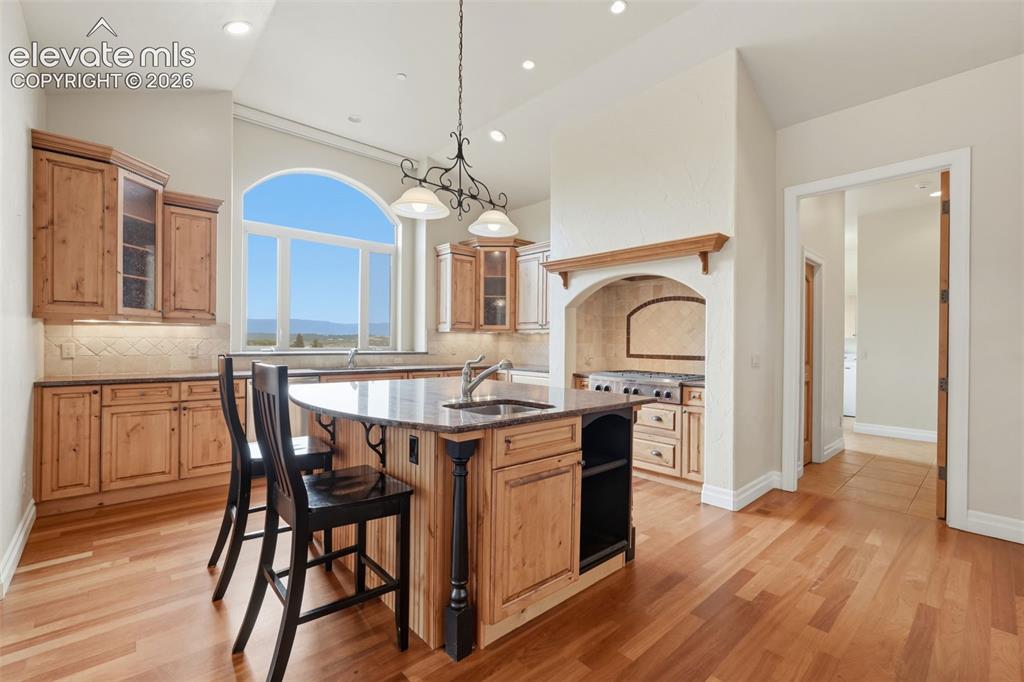 Image 23 of 50: Kitchen featuring wood-finish flooring, custom wood cabinetry, and a large