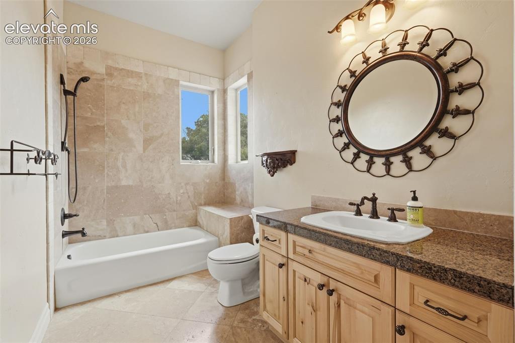 Image 28 of 50: Bathroom featuring a light-toned tile floor, a built-in tub with dark bronz
