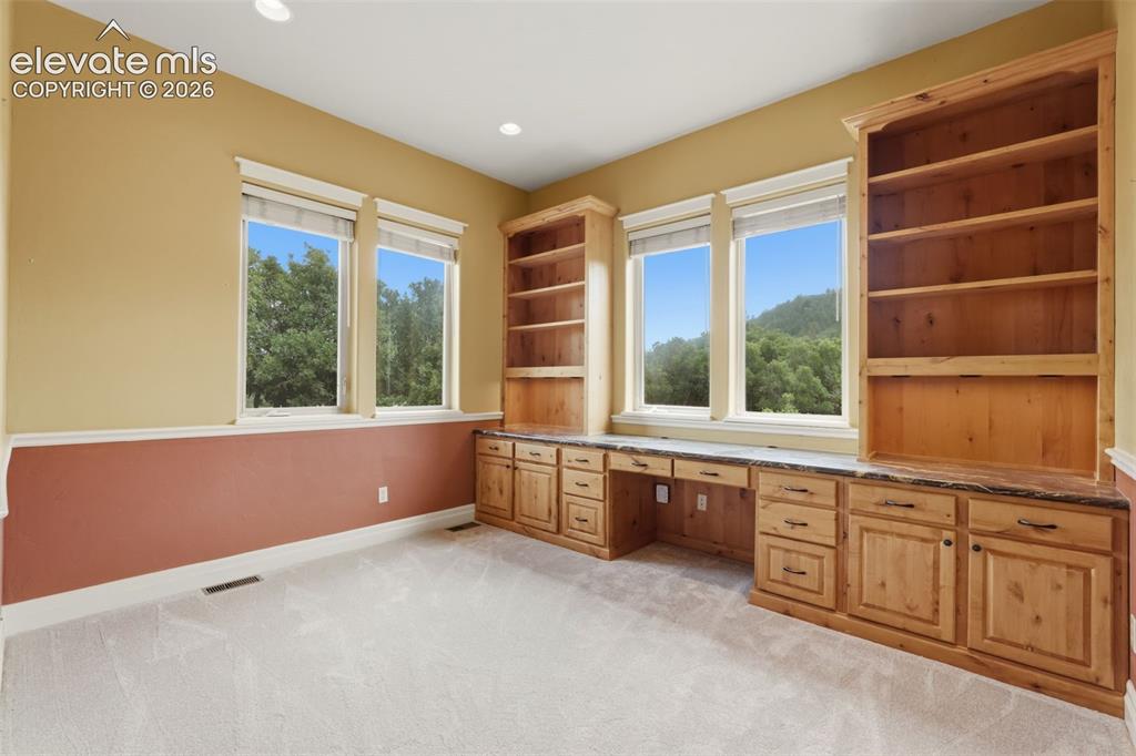 Image 30 of 50: Built-in wood cabinetry with stone countertops and two integrated desks