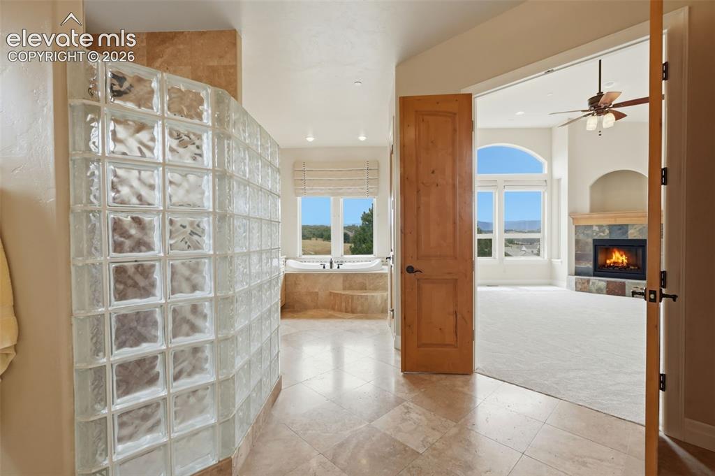 Image 34 of 50: Glass block shower enclosure with a built-in soaking tub, tile flooring, an