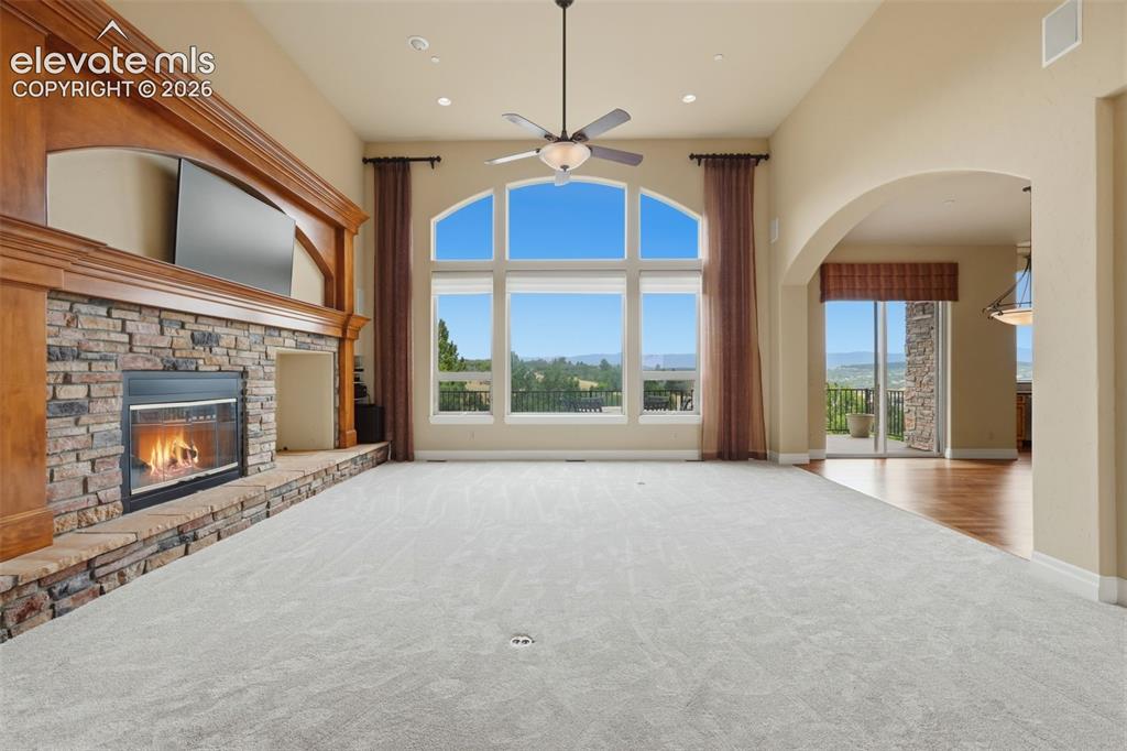 Image 4 of 50: Spacious room featuring a stone-faced fireplace with a wood mantel, expansi