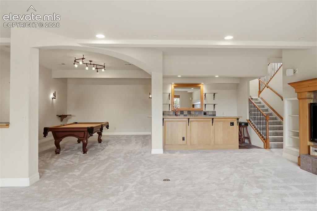 Image 40 of 50: Lower level featuring light gray carpeting, a built-in wet bar with light w