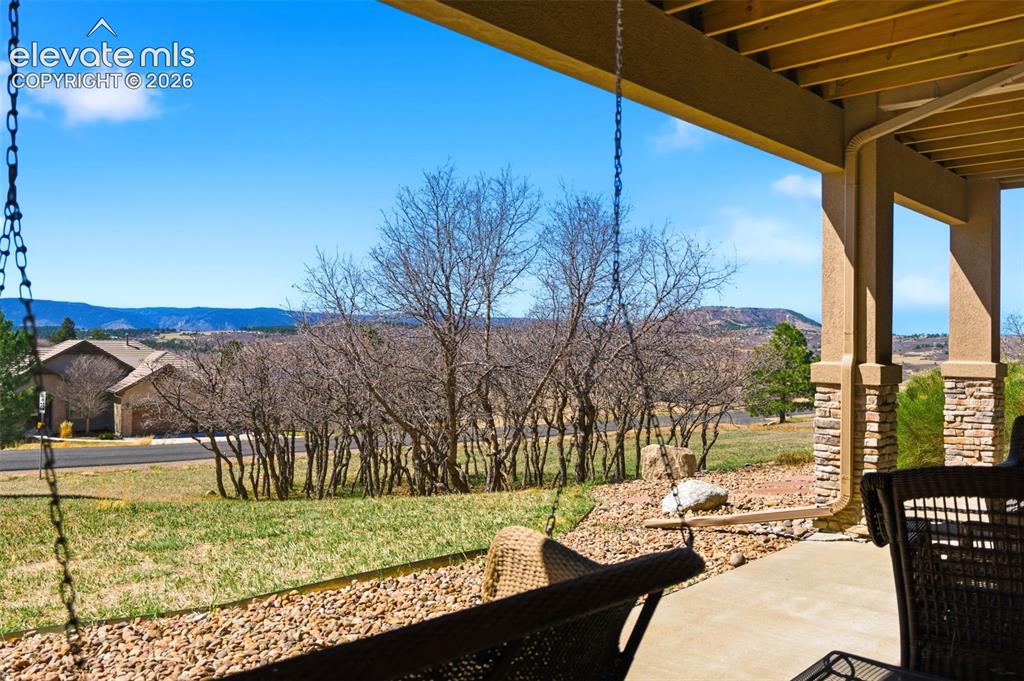 Image 43 of 50: Covered patio with a concrete surface, stone-clad columns, and a natural la