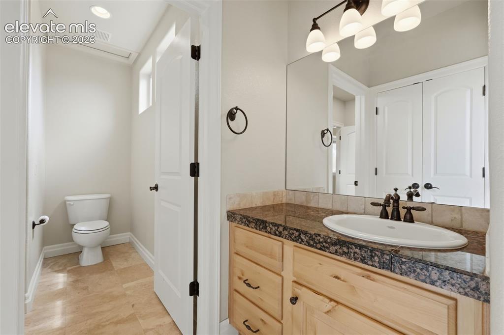 Image 45 of 50: Bathroom featuring a natural wood vanity with dark hardware, a surface-moun