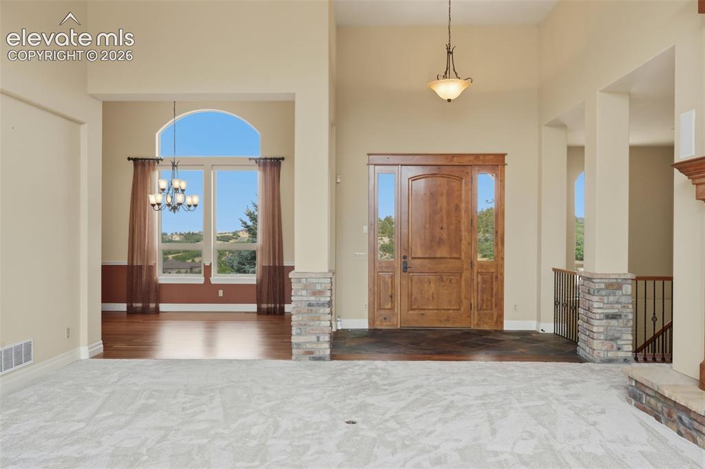 Image 9 of 50: Two-story entryway featuring a natural wood front door with sidelights, a l