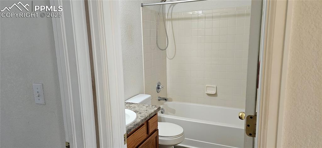 Image 21 of 26: Full bathroom with a textured wall, vanity, and shower / tub combination