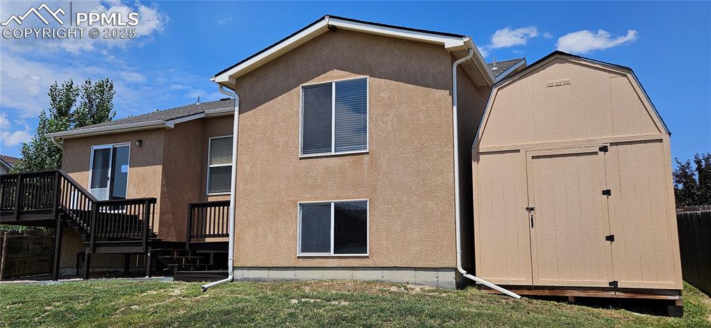 Image 5 of 26: Rear view of property with stairway, a storage shed, a deck, and stucco sid