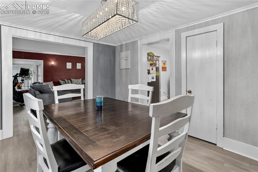 Image 15 of 50: Dining area featuring light wood-type flooring, textured wall, and chandeli