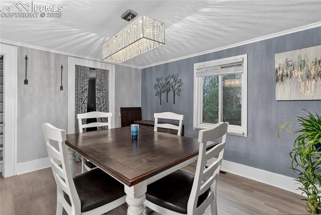 Image 17 of 50: Dining area with a textured wall, wood finished floors, crown molding, and 