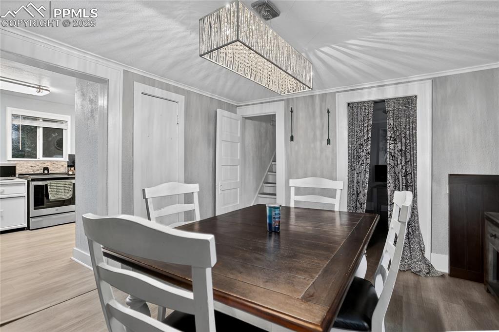 Image 18 of 50: Dining area featuring wood finished floors, stairs, ornamental molding, and