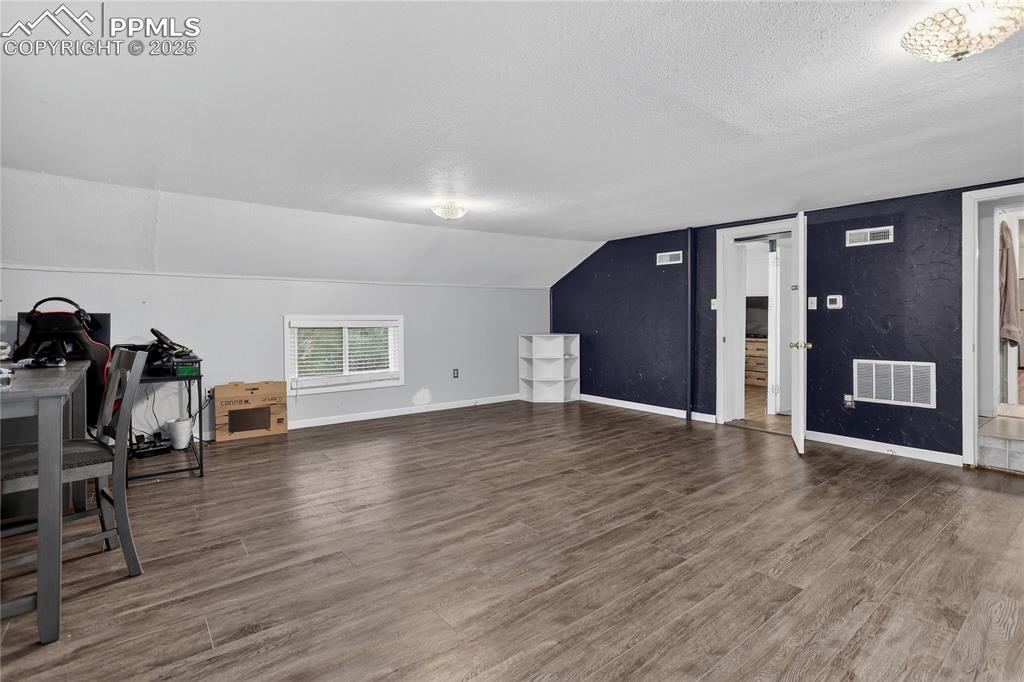 Image 21 of 50: Additional living space featuring wood finished floors, lofted ceiling, and