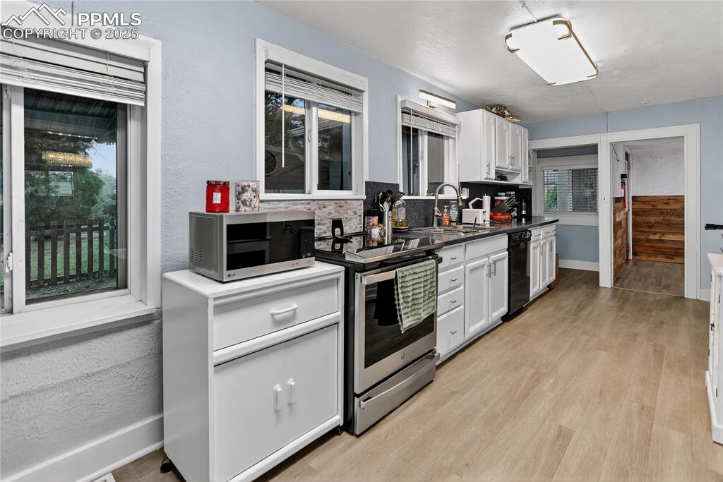 Image 28 of 50: Kitchen featuring white cabinetry,textured walls, stainless steel appliance