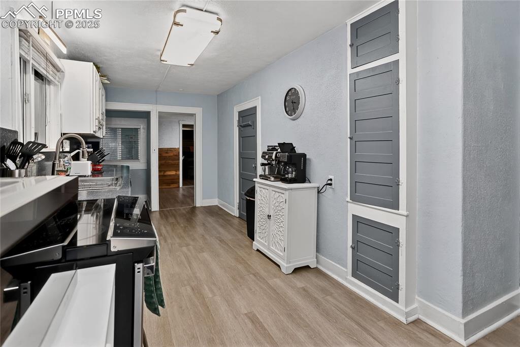 Image 29 of 50: Kitchen featuring white cabinetry, light wood-style flooring, and range