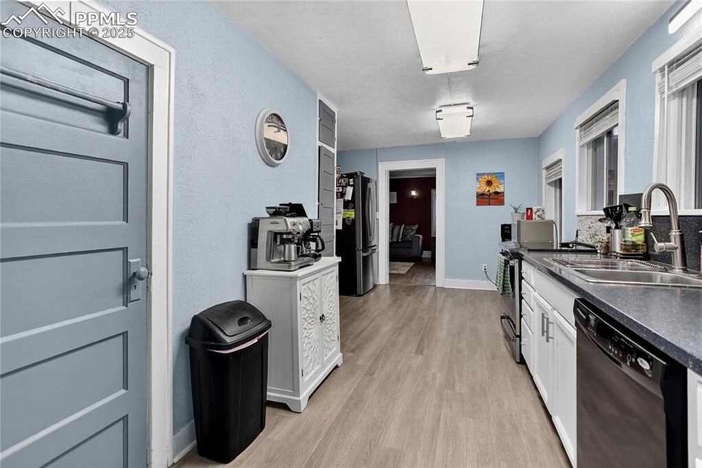 Image 31 of 50: Kitchen with dark countertops, light wood-style flooring, stainless steel a