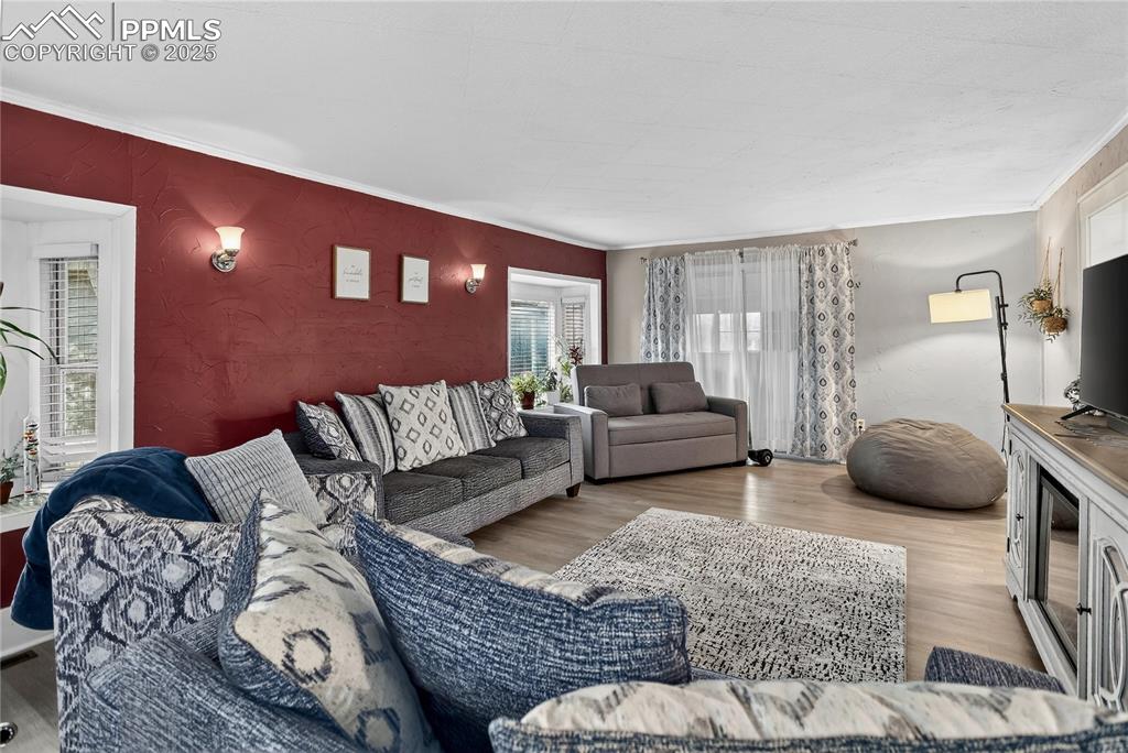 Image 32 of 50: Living area with wood finished floors, a textured wall, and ornamental mold