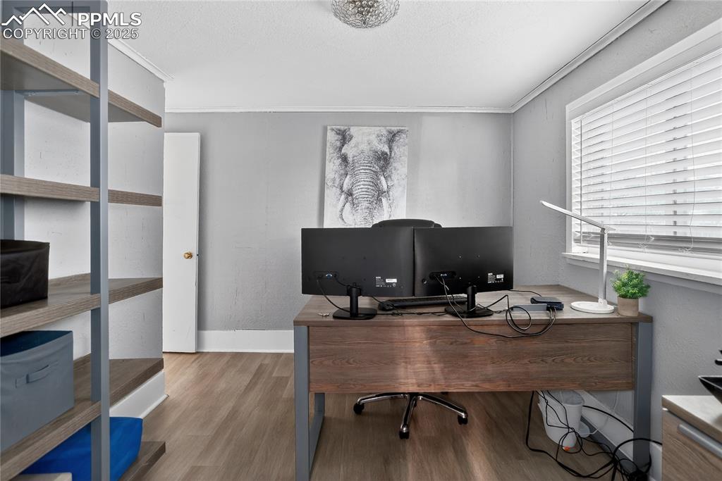Image 43 of 50: Office area with wood finished floors, ornamental molding, textured walls