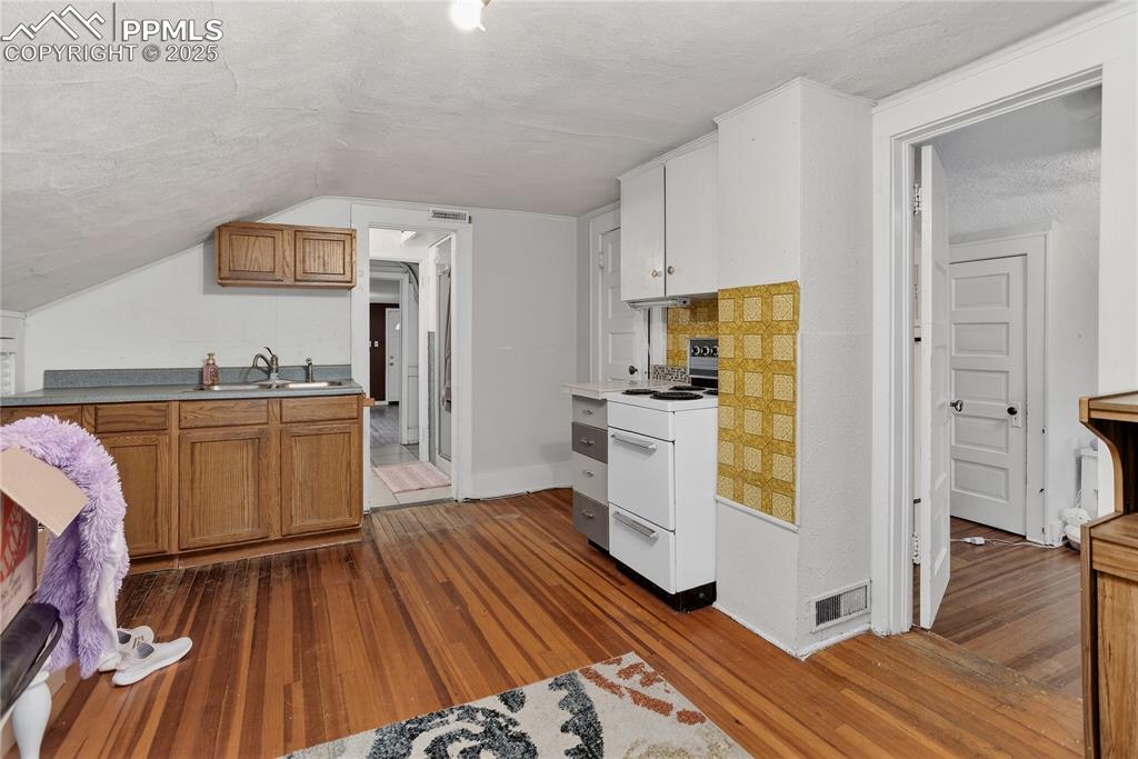 Image 47 of 50: Kitchen featuring a textured ceiling, electric stove, dark wood-style floor