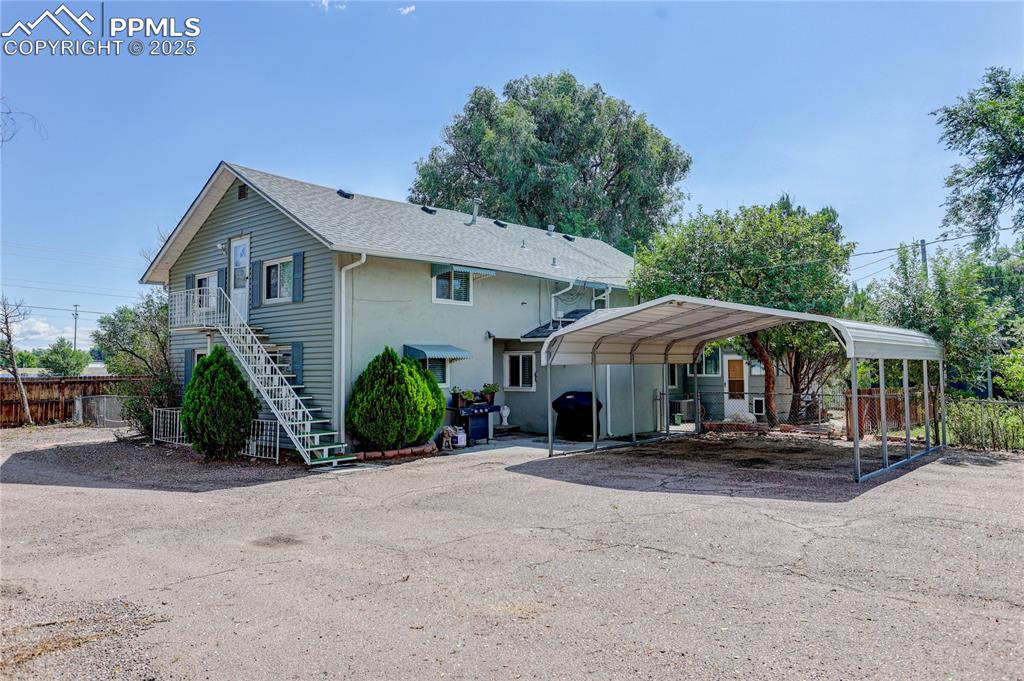 Image 50 of 50: Back of property featuring stairs, a detached carport, and asphalt driveway