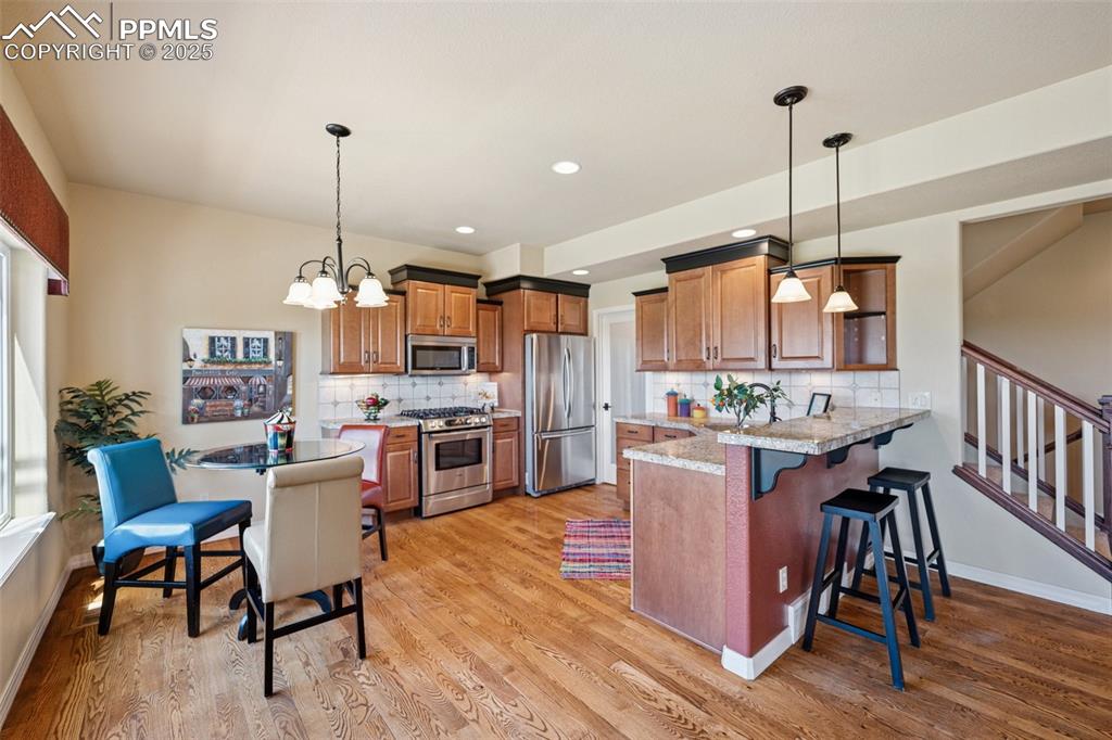 Image 12 of 47: Kitchen with stainless steel appliances, a peninsula, brown cabinetry, a ki