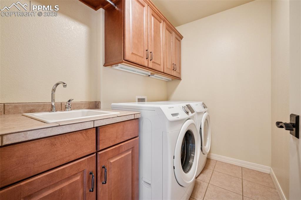 Image 21 of 47: Laundry room with cabinet space, separate washer and dryer, and light tile 