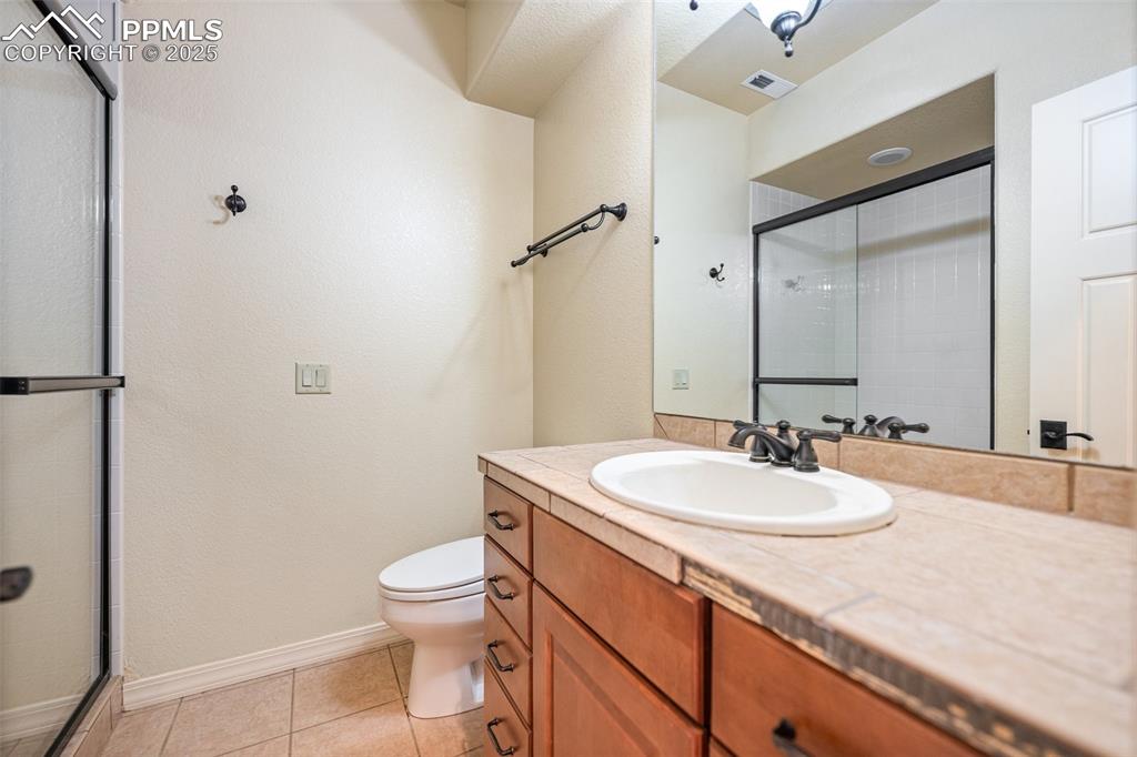 Image 32 of 47: Bathroom featuring vanity, an enclosed shower, and tile patterned flooring