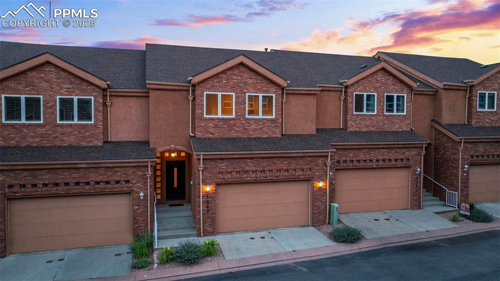 Image 38 of 47: Multi unit property with brick siding, an attached garage, roof with shingl