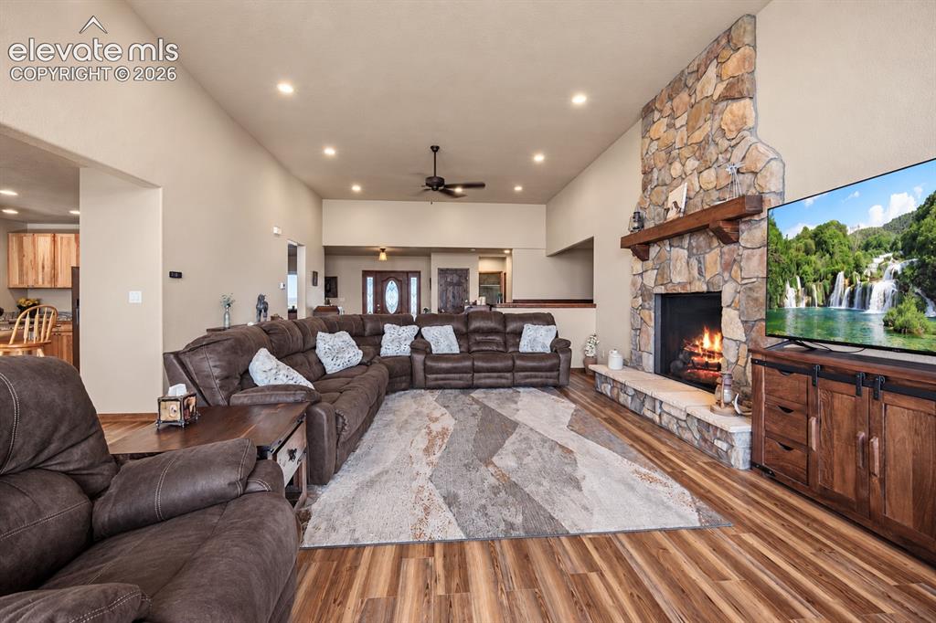 Image 3 of 49: Vaulted ceiling with recessed lighting, stone-front fireplace with a wood m
