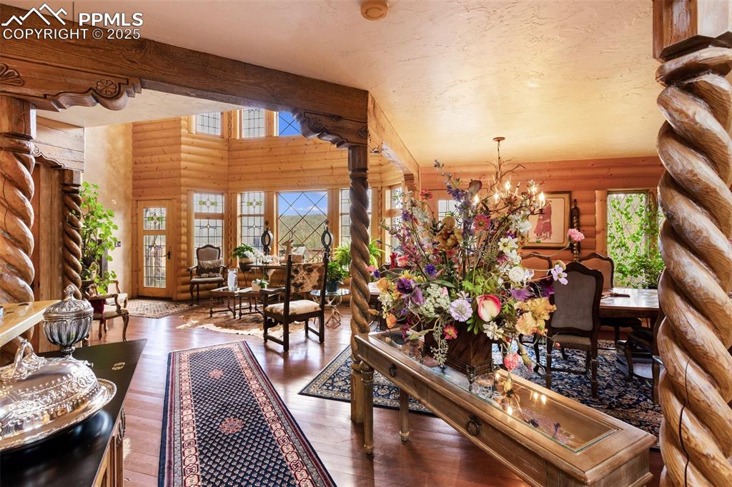 Image 10 of 50: Living area featuring a chandelier, log walls, wood finished floors, and or