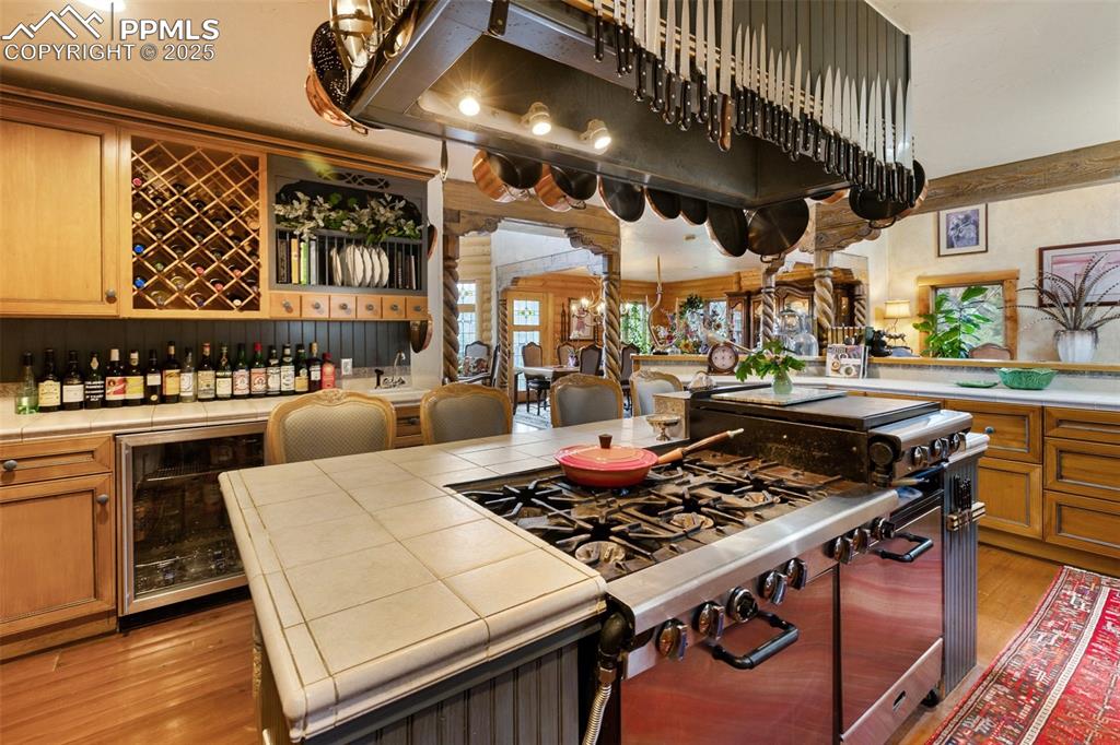 Image 17 of 50: Kitchen featuring beverage cooler, tile countertops, light wood-style floor