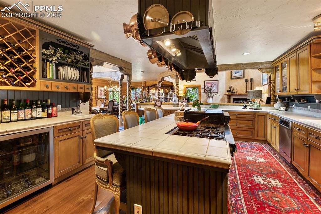 Image 18 of 50: Kitchen with tile counters, stainless steel dishwasher, beverage cooler, op