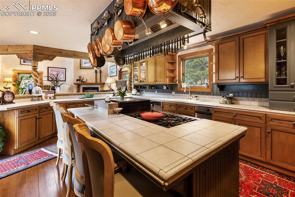 Image 19 of 50: Kitchen with tile counters, gas cooktop, a kitchen island, open shelves, an