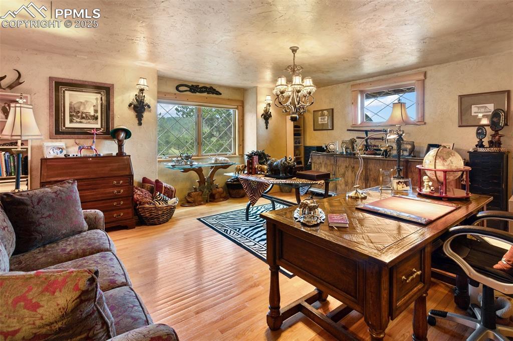 Image 20 of 50: Office space with a textured wall, wood finished floors, and a chandelier