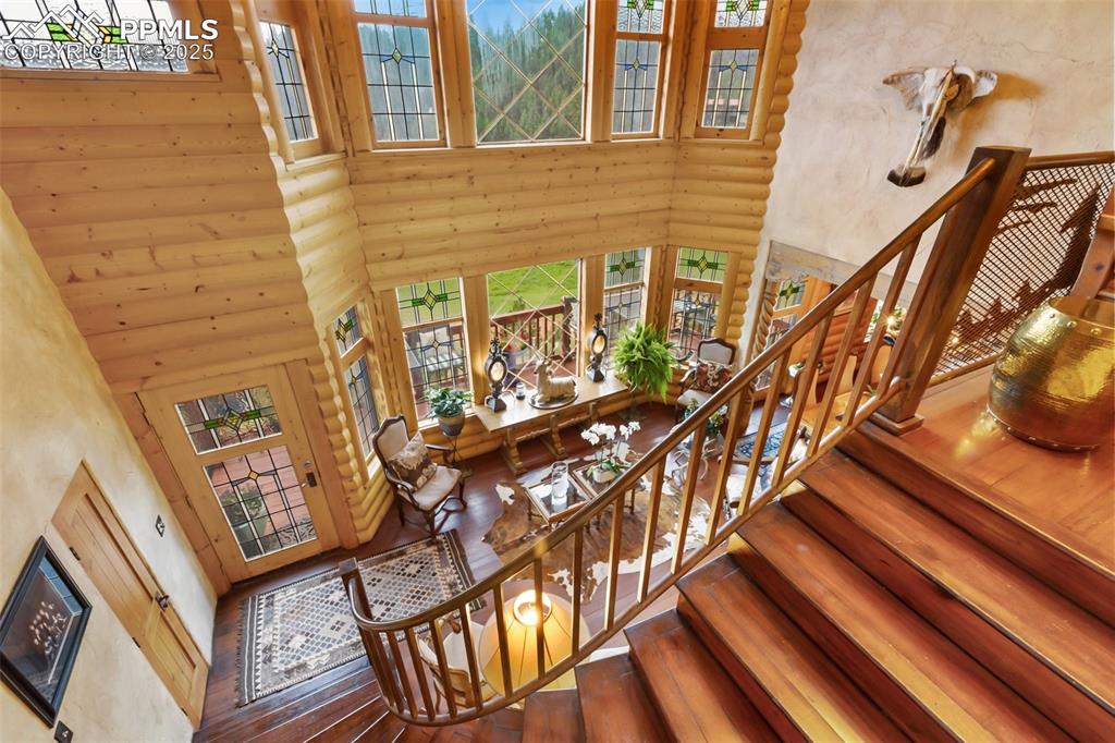 Image 23 of 50: Stairs with a high ceiling, log walls, and hardwood / wood-style flooring