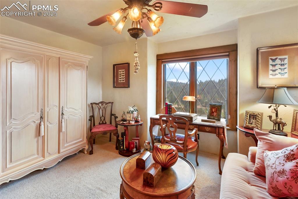 Image 29 of 50: Living area with light carpet, a ceiling fan, and an office area