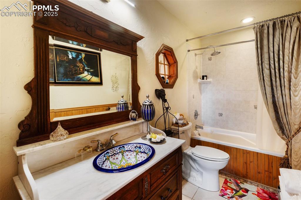 Image 30 of 50: Bathroom featuring vanity, shower / bath combination with curtain, and tile