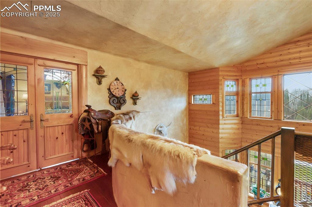 Image 34 of 50: Foyer entrance featuring wood finished floors, log walls, lofted ceiling, a