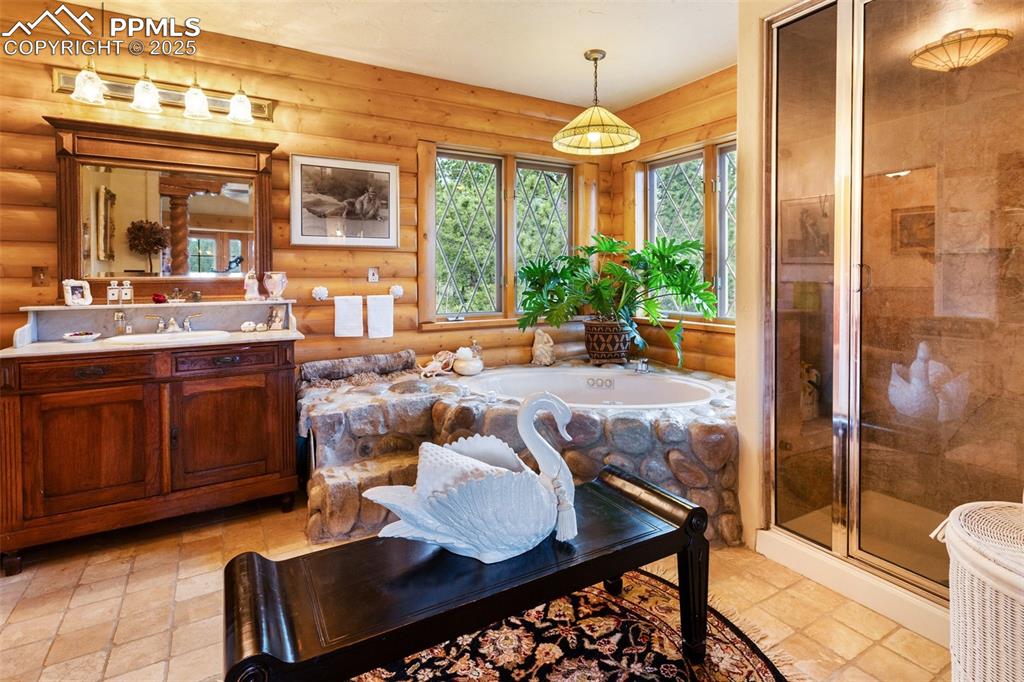 Image 37 of 50: Full bathroom with rustic walls, vanity, a garden tub, and a shower stall