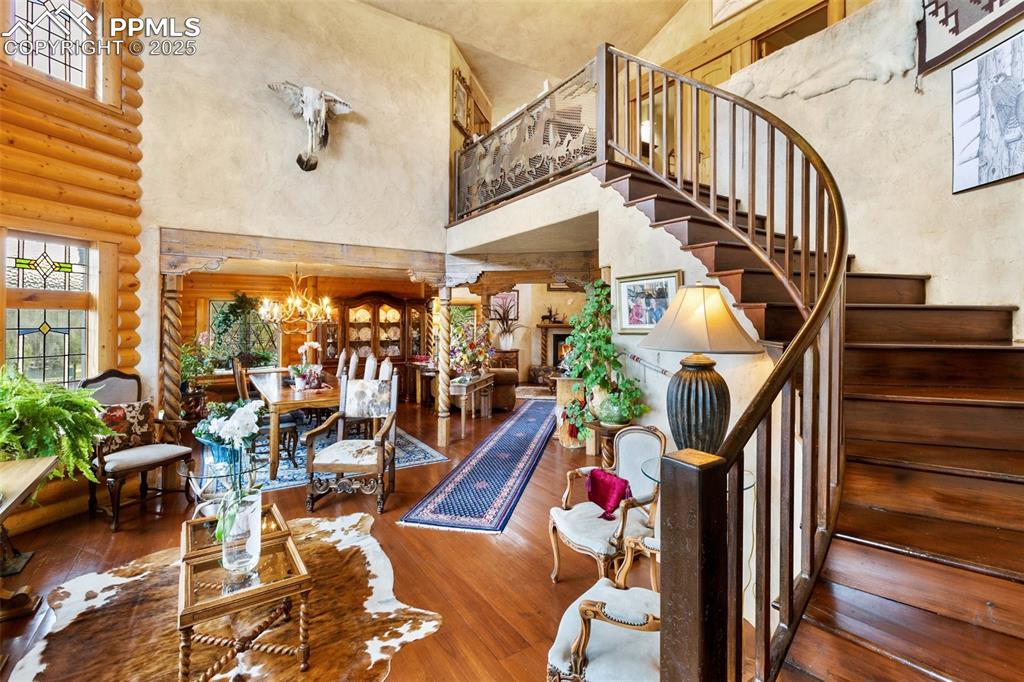 Image 4 of 50: Stairway featuring a high ceiling, rustic walls, wood finished floors, and