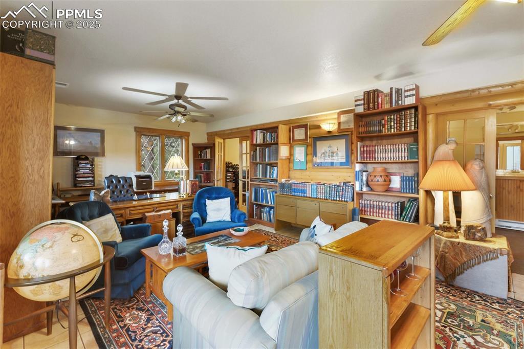 Image 40 of 50: Tiled living area featuring a ceiling fan and a baseboard heating unit
