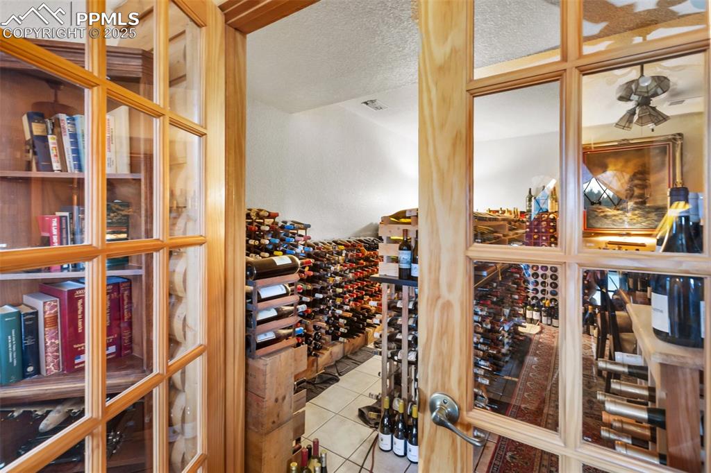 Image 43 of 50: Wine room with tile patterned floors and a textured ceiling