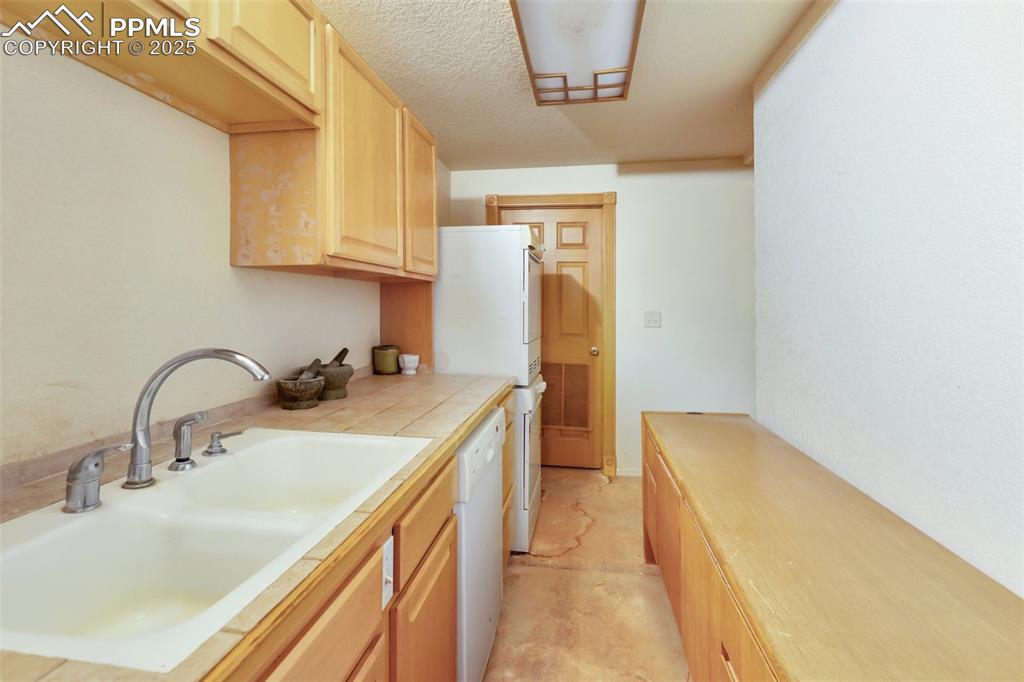 Image 46 of 50: Kitchen featuring light brown cabinets, white appliances, and tile countert