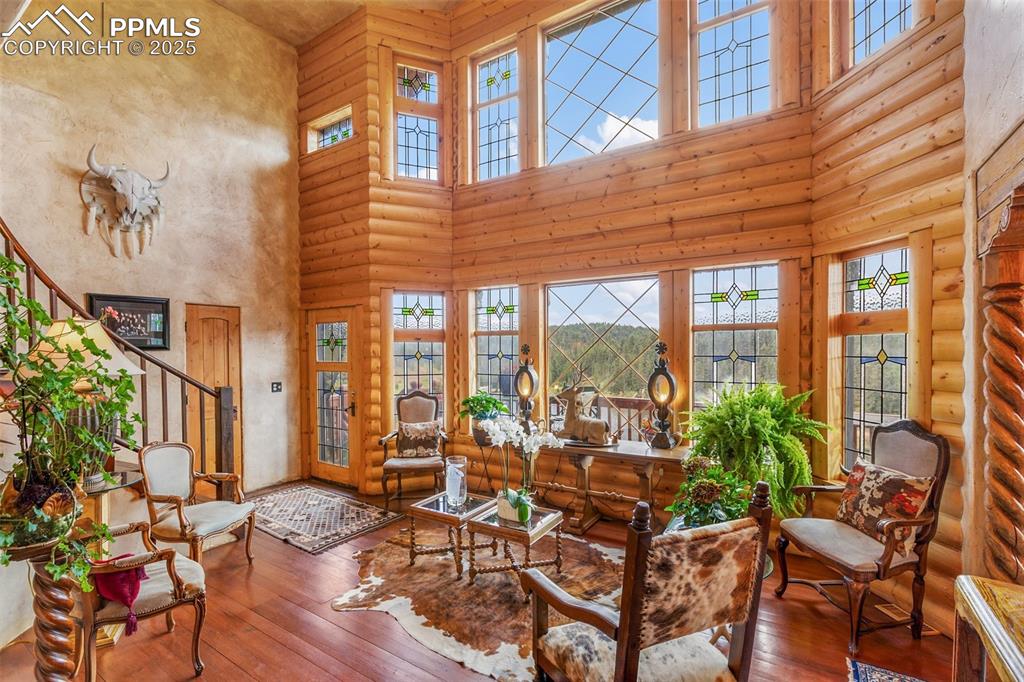 Image 7 of 50: Living room featuring a high ceiling, wood-type flooring, and rustic walls