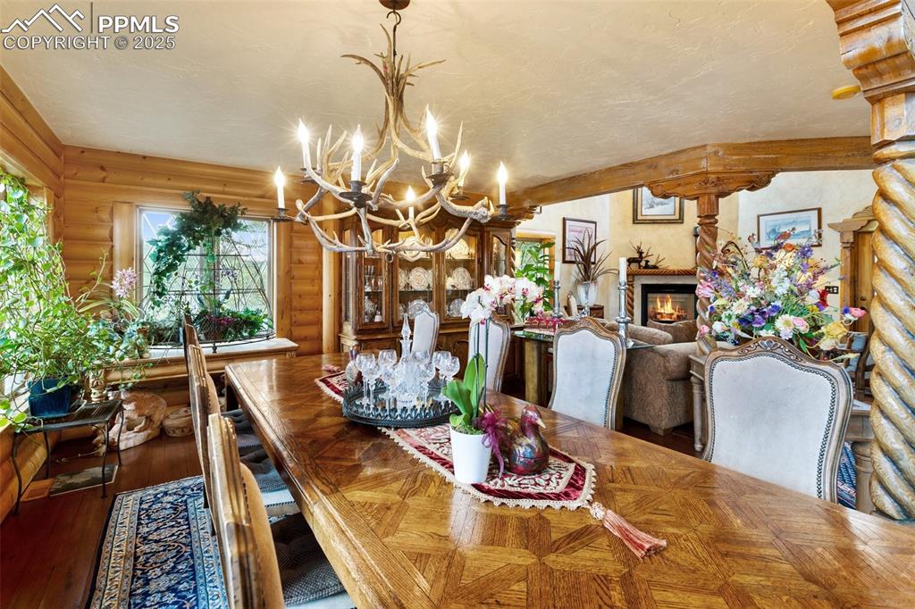 Image 8 of 50: Dining space featuring rustic walls, a chandelier, a premium fireplace, and