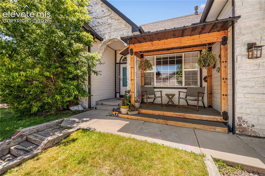 Image 3 of 50: Stone veneer exterior featuring a covered entry porch with wood columns and