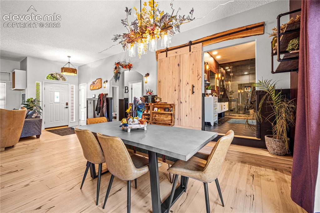 Image 8 of 50: Light wood-finish flooring, brick archways, modern black walls, and French