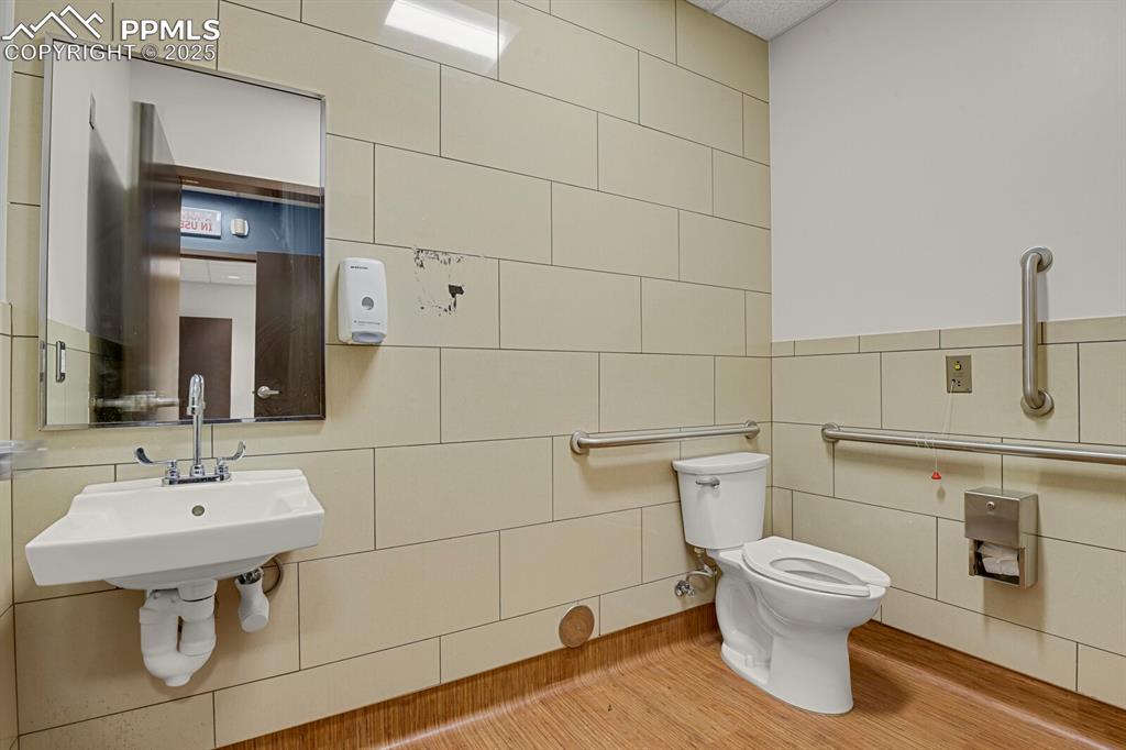 Image 10 of 43: Bathroom with tile walls and wood finished floors