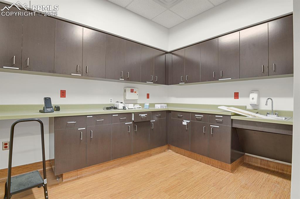 Image 21 of 43: Kitchen with a paneled ceiling, light countertops, and dark brown cabinetry