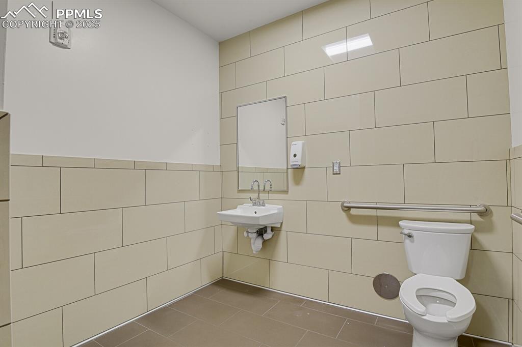 Image 28 of 43: Half bath with tile walls and tile patterned floors