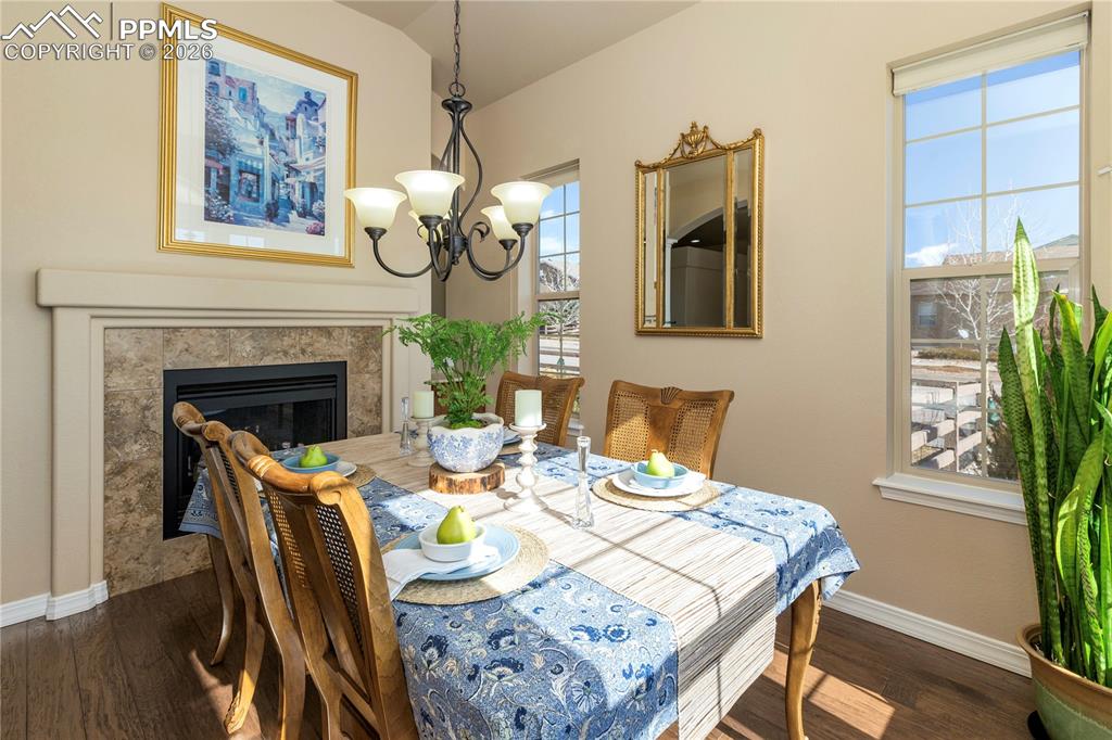 Image 16 of 50: Dining area with dark wood-style flooring, hanging lights, a glass covered 