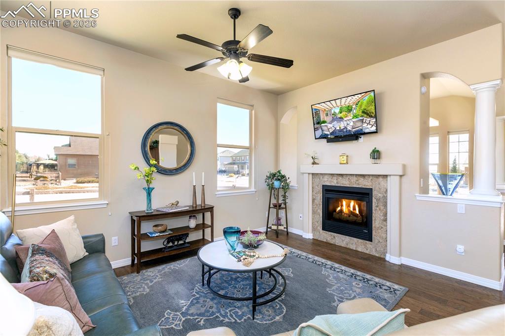 Image 19 of 50: Living area with arched walkways, dark wood-style floors, a ceiling fan, an
